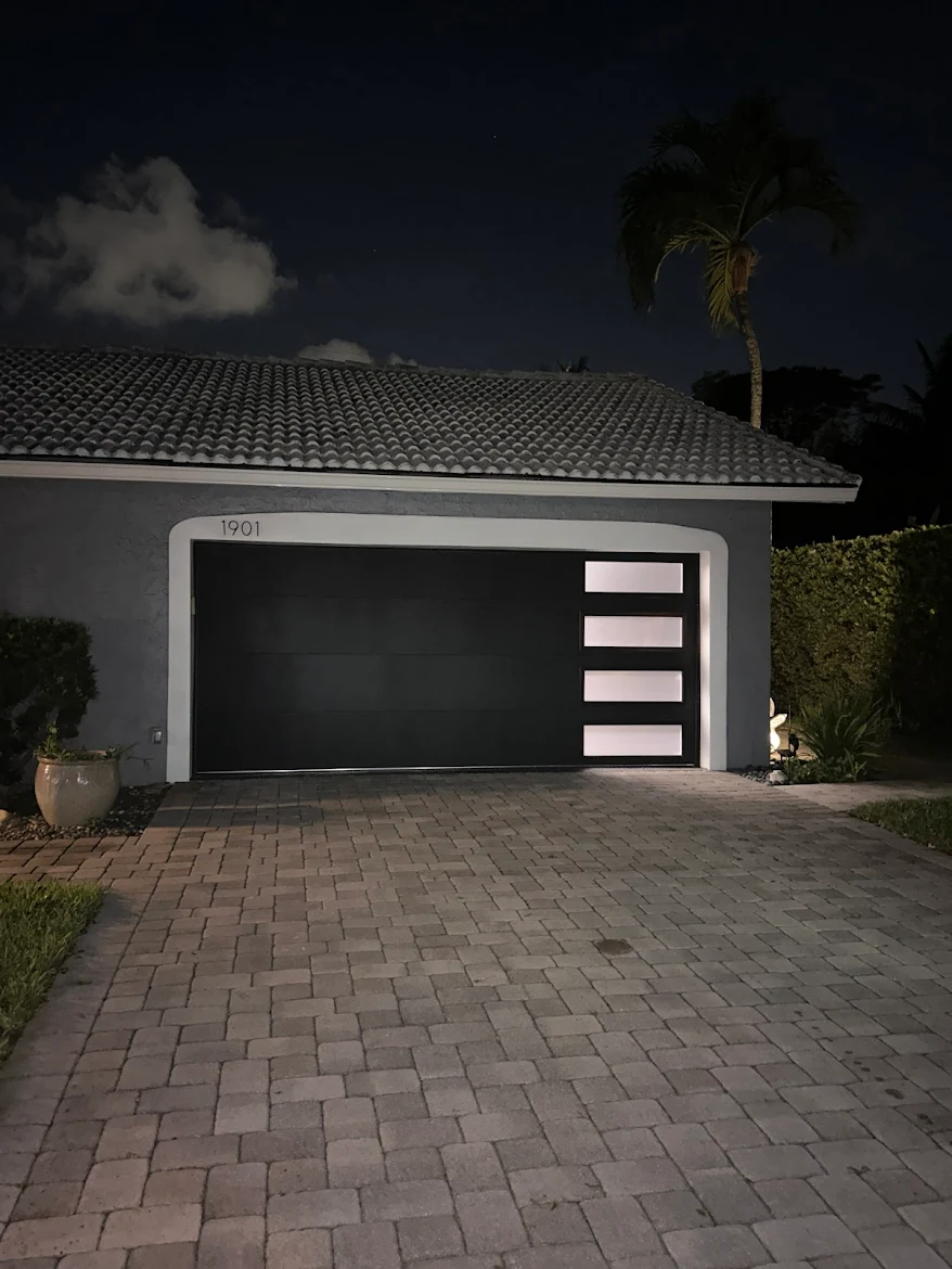Modern black glass-panel garage door installed by Miller's in South Florida